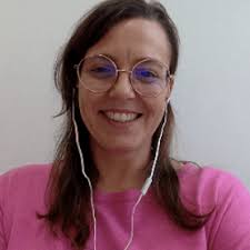 Mulher branca, de rosto oval e expressão serena, aparentando 40 anos. Tem cabelos castanho-claros, médios e soltos. Olhos castanhos, com sobrancelhas arqueadas. Usa óculos de grau redondos e discretos, além de vestir uma blusa rosa.